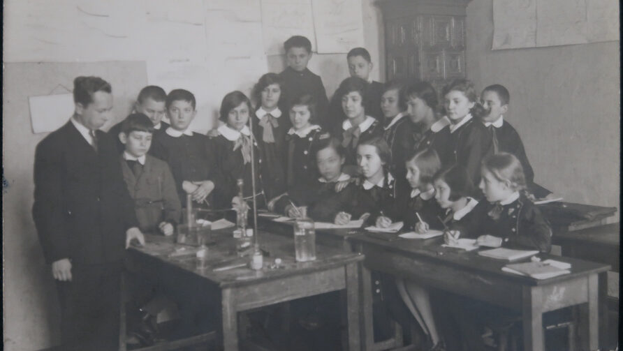 A group of young pupils watching a teacher conduct a chemistry experiment.