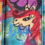 Graffiti art depicting feminine horse, possibly unicorn, with a long, red mane.