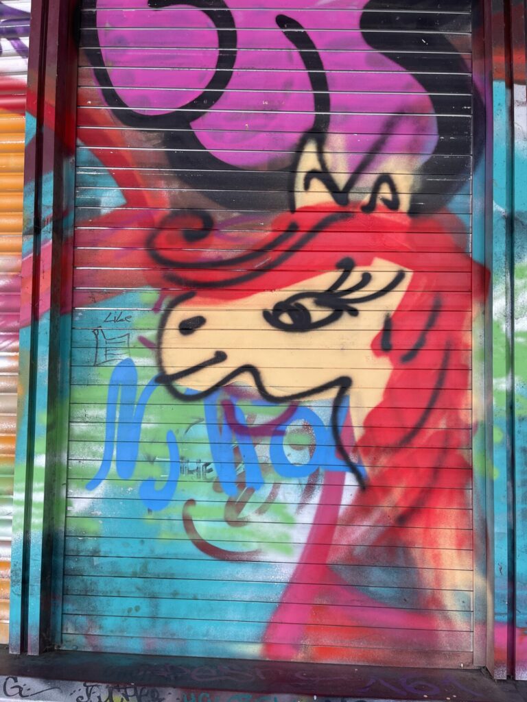 Graffiti art depicting feminine horse, possibly unicorn, with a long, red mane.