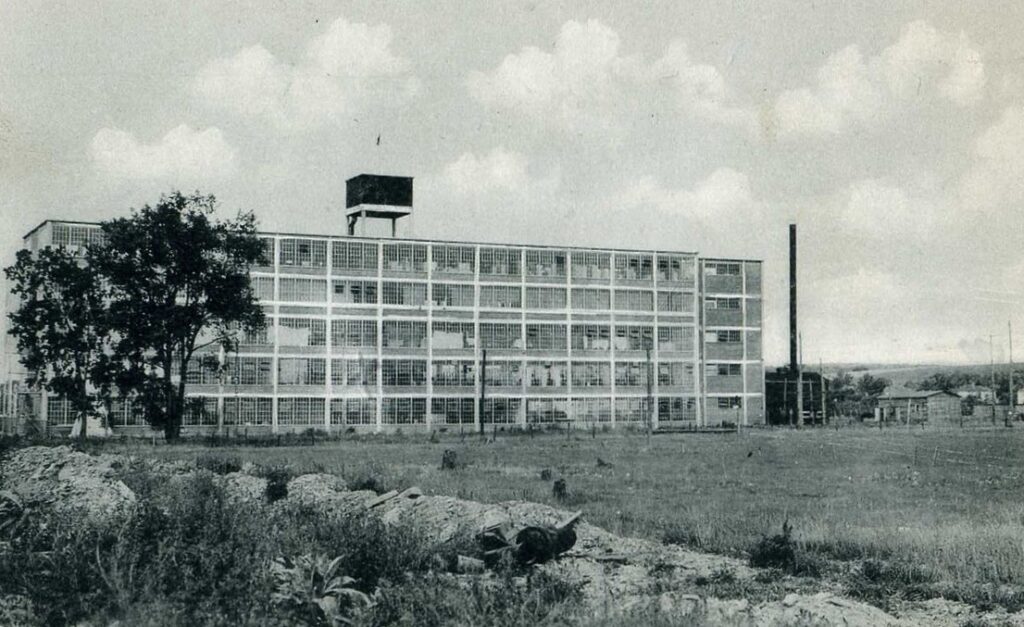 Rectangular, industrial building with a watchtower and flag on top.
